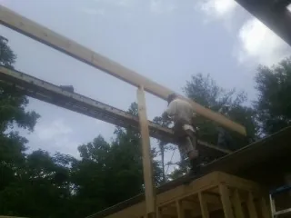Carpenter setting a ridge beam over a new addition frame — Ice Dam Removal by Roofing Brothers in Malverne