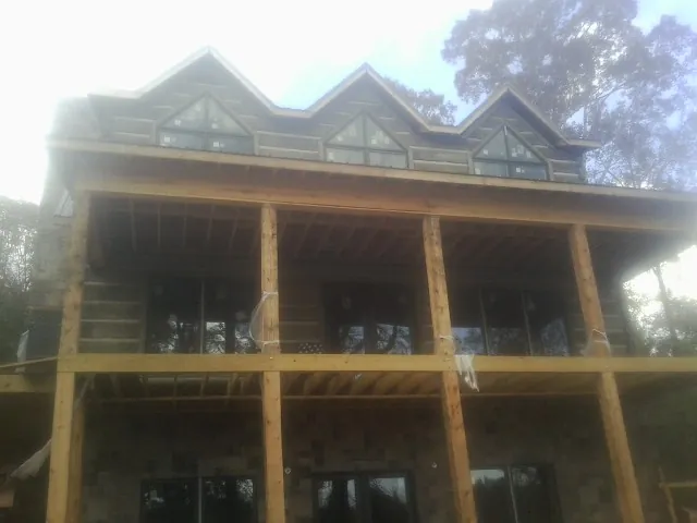 Dormers and porch framing on a large log home under construction — Roof Coating work by our crew in Malverne