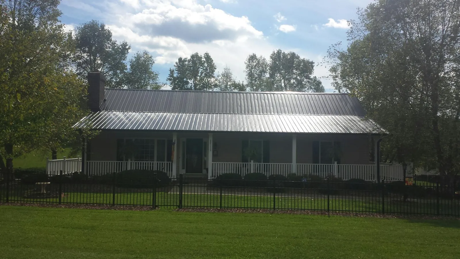 Gray metal roof on a brick ranch with a full width front porch — Gutter Guard Installation work by our crew in Malverne