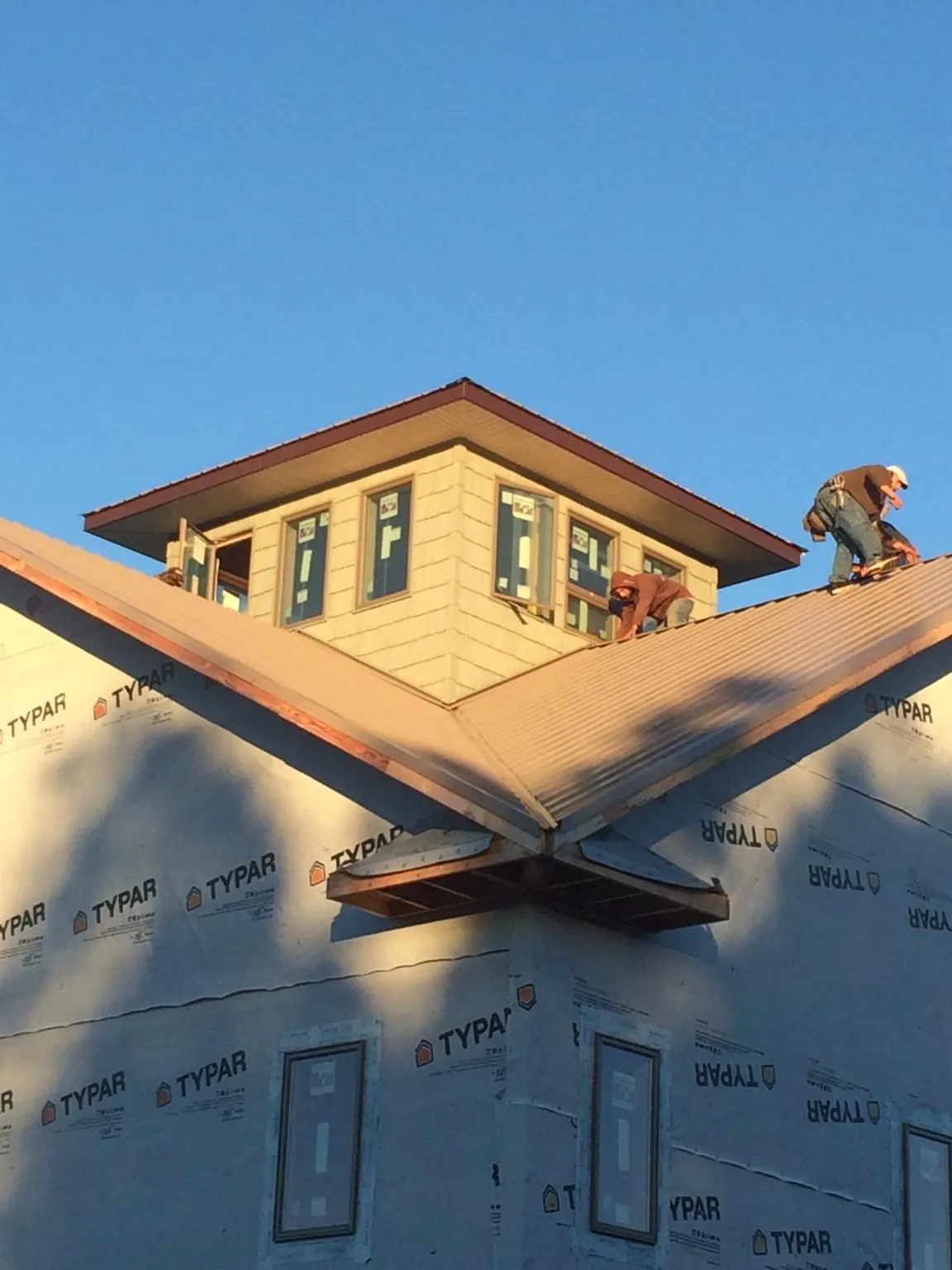 Roofers working around a rooftop cupola on a new metal roof at sunset — Roof Waterproofing in Malverne by Roofing Brothers